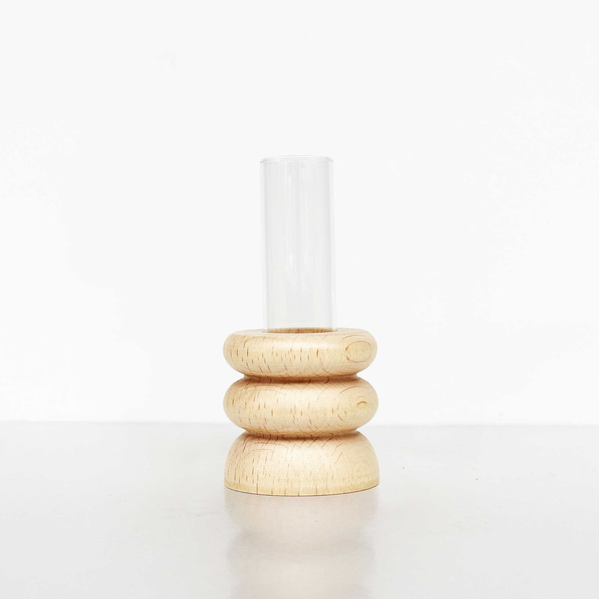 playful short totem wooden vase with a single bright flower on a sunlit windowsill