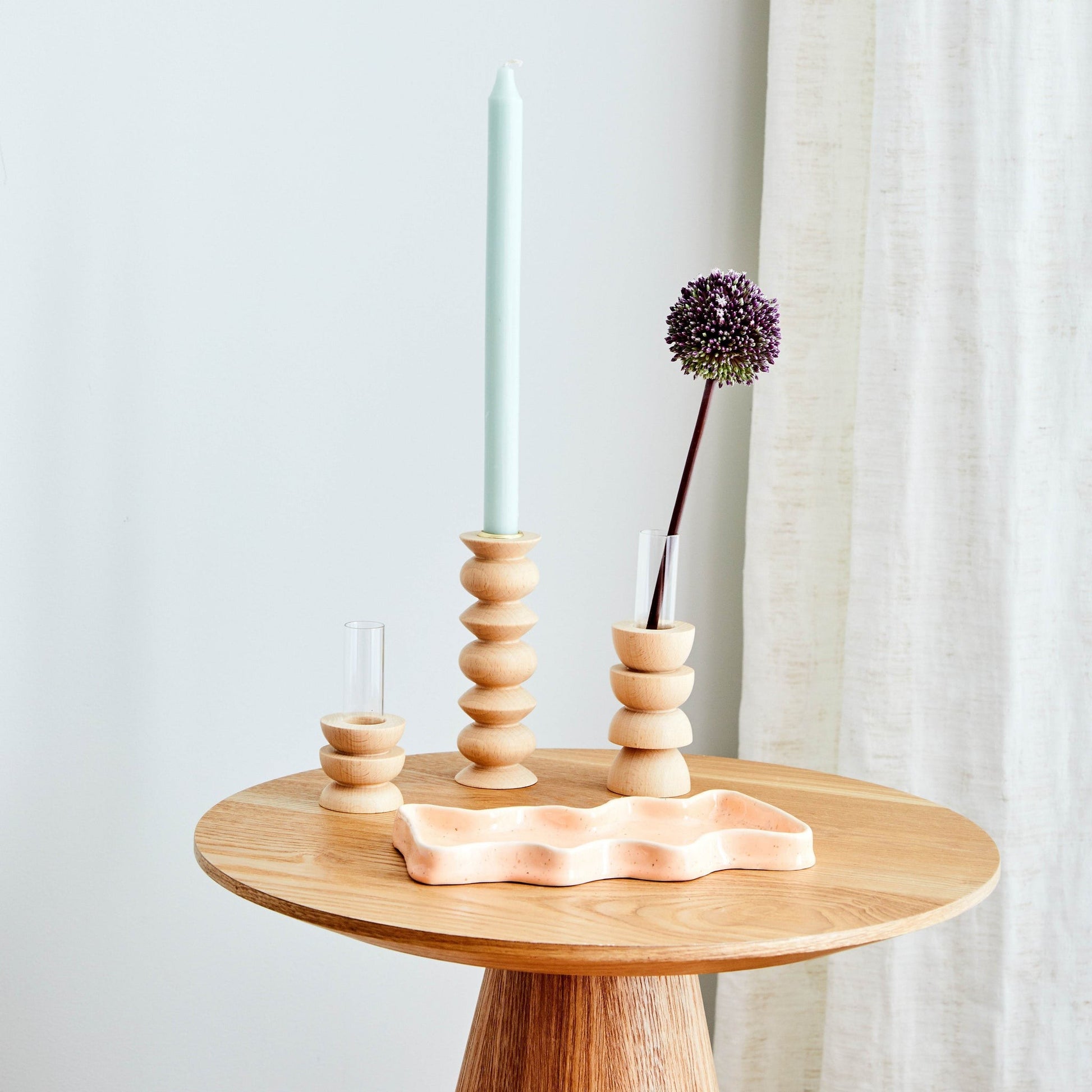 softly lit short totem vase with a single dried flower on a cozy shelf