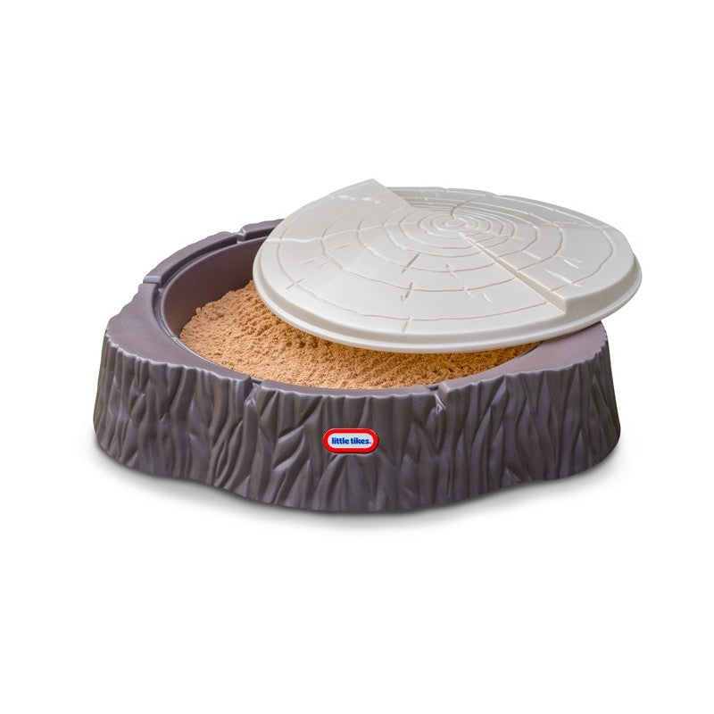 kids laughing while building sandcastles in a whimsical tree trunk sandbox