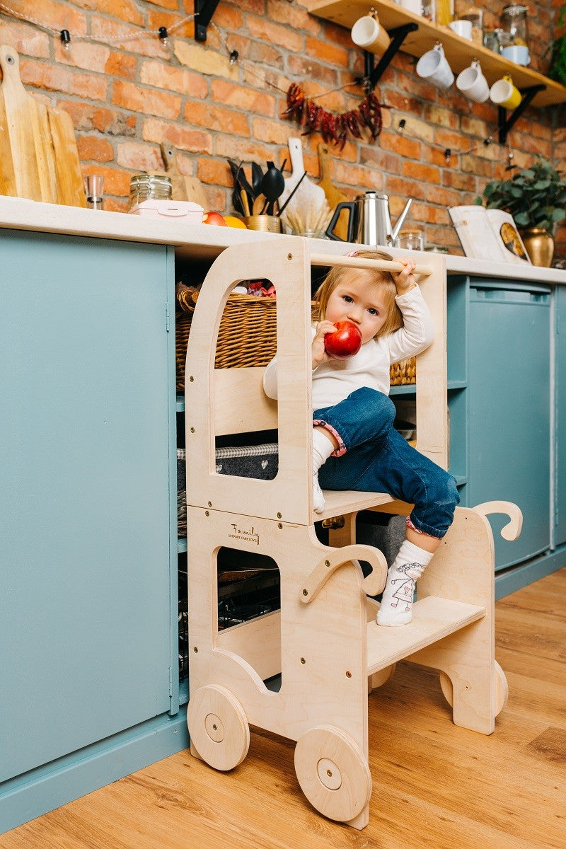 a child in a cotton outfit stands at the warm yellow montessori table, focused on stirring a bowl