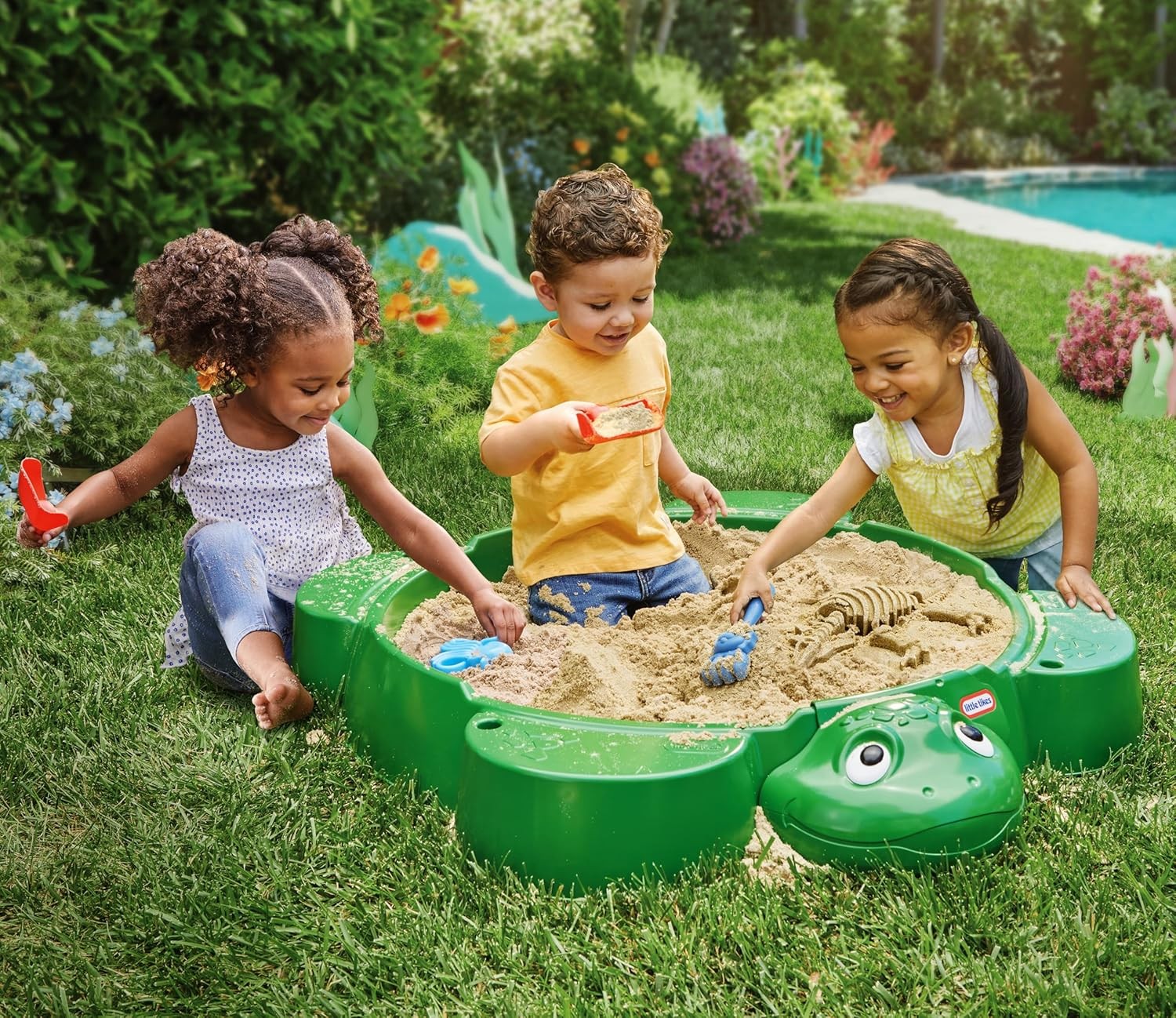 bold front view of the little tikes turtle sandbox with its shell lid open in a sunny backyard