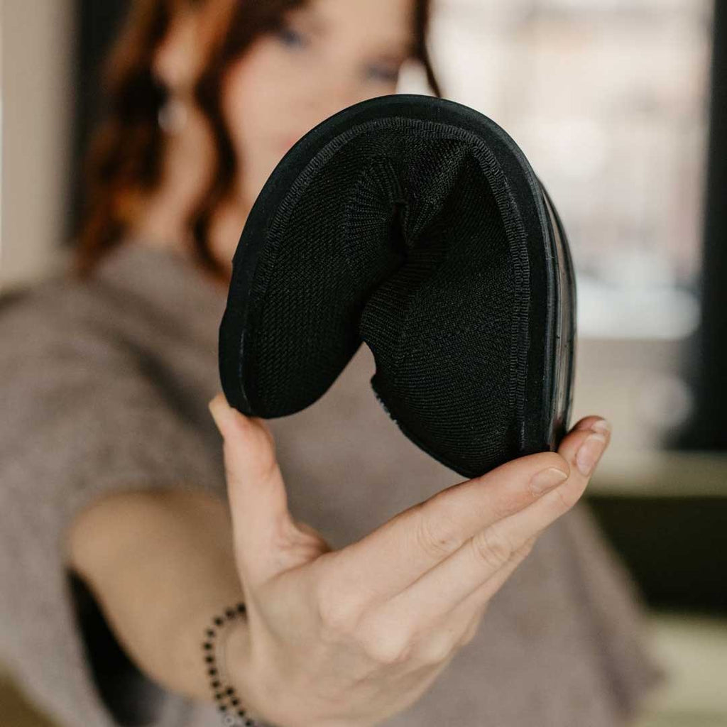 soft grey upcycled ballerina shoes with recycled tyre soles, nestled on a cozy wool rug in natural light