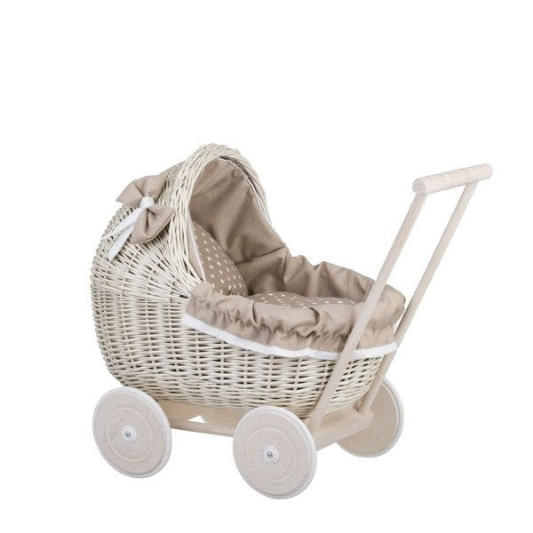 softly lit whitewashed wicker doll pram with cozy beige bedding from a gentle side angle