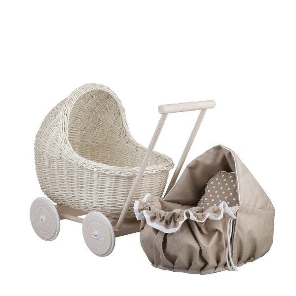 a child's hand gently tucking a doll into the beige bedding of a whitewashed wicker pram