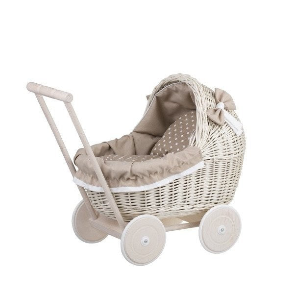 a child's hand gently tucking a doll into the beige bedding of a whitewashed wicker pram