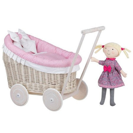 confident close-up of a charming whitewashed wicker doll pram with plush pink bedding