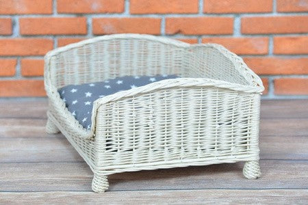 softly lit whitewashed wicker pet bed with plush cushion in a cozy nursery setting