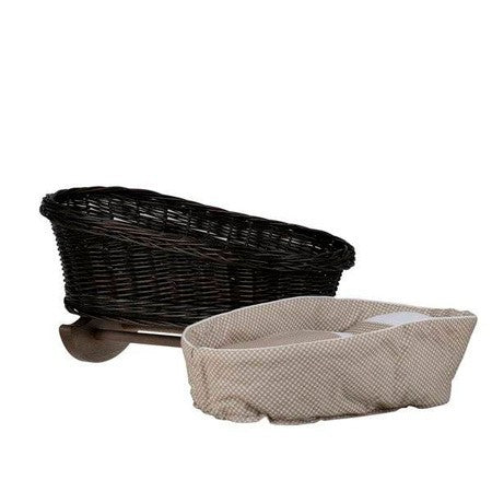 softly lit wicker doll cradle with beige checkered bedding in a cozy nursery corner
