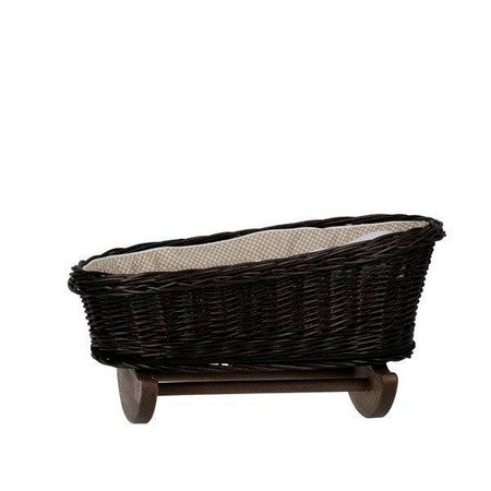 a child's hand gently rocking the wicker doll cradle with beige checkered bedding