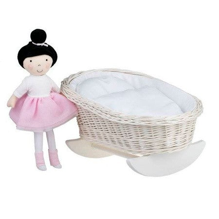 a playful kid gently rocking the wicker doll cradle with white bedding