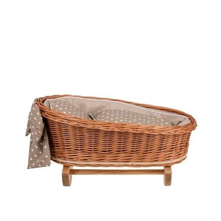 softly lit wicker doll cradle with beige checkered bedding and a plush teddy bear