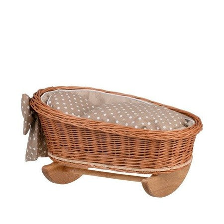 playful close-up of the wicker rocking cradle's cozy beige bedding and white trim