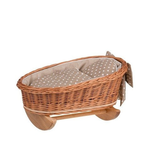 a doll's wicker rocking cradle with beige checkered bedding in soft morning light