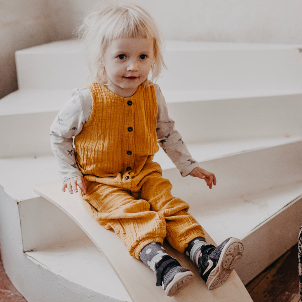 a person using a wooden balance board on a flat floor to improve stability and core strength