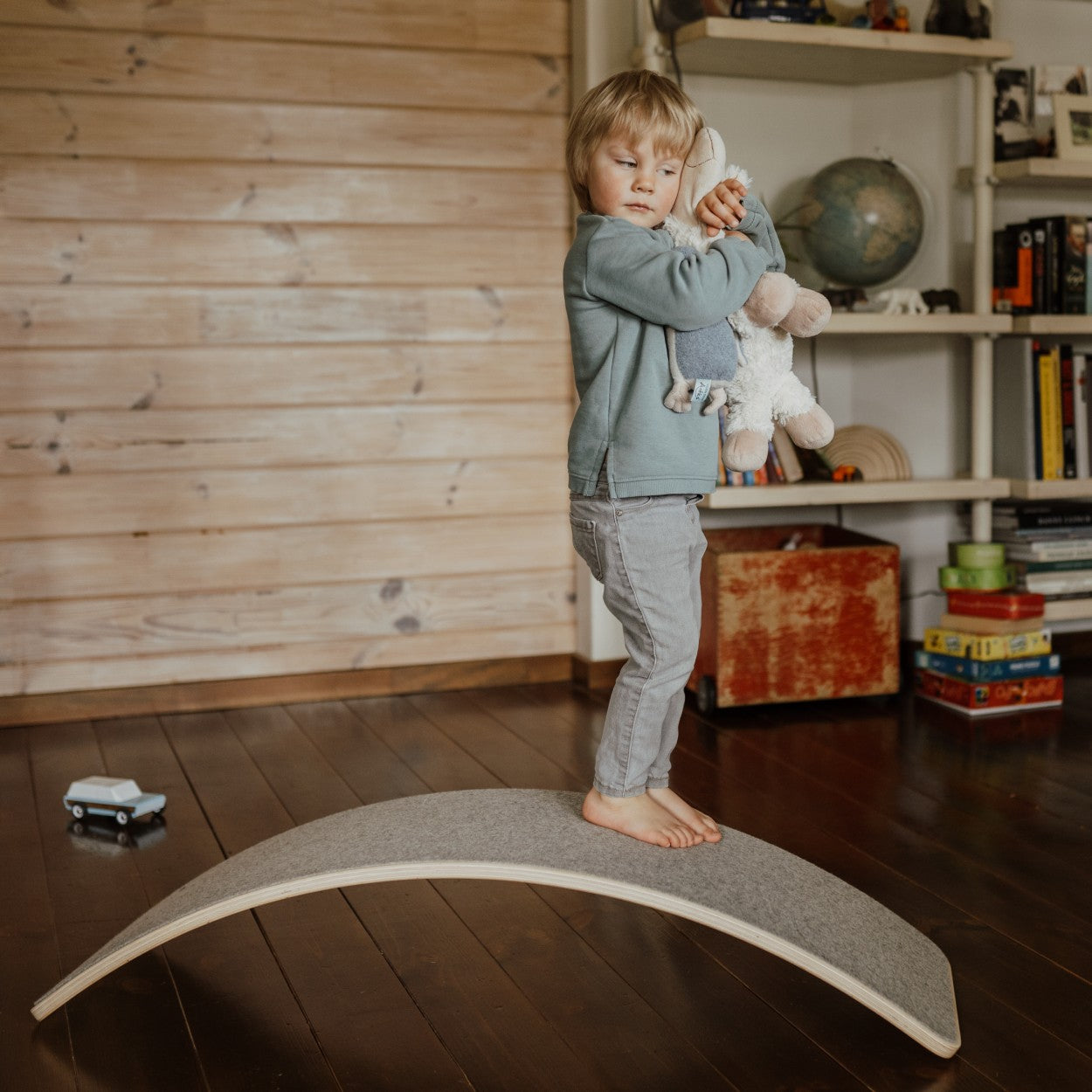 a child's feet wobbling on a grey felt balance board in a sunlit playroom