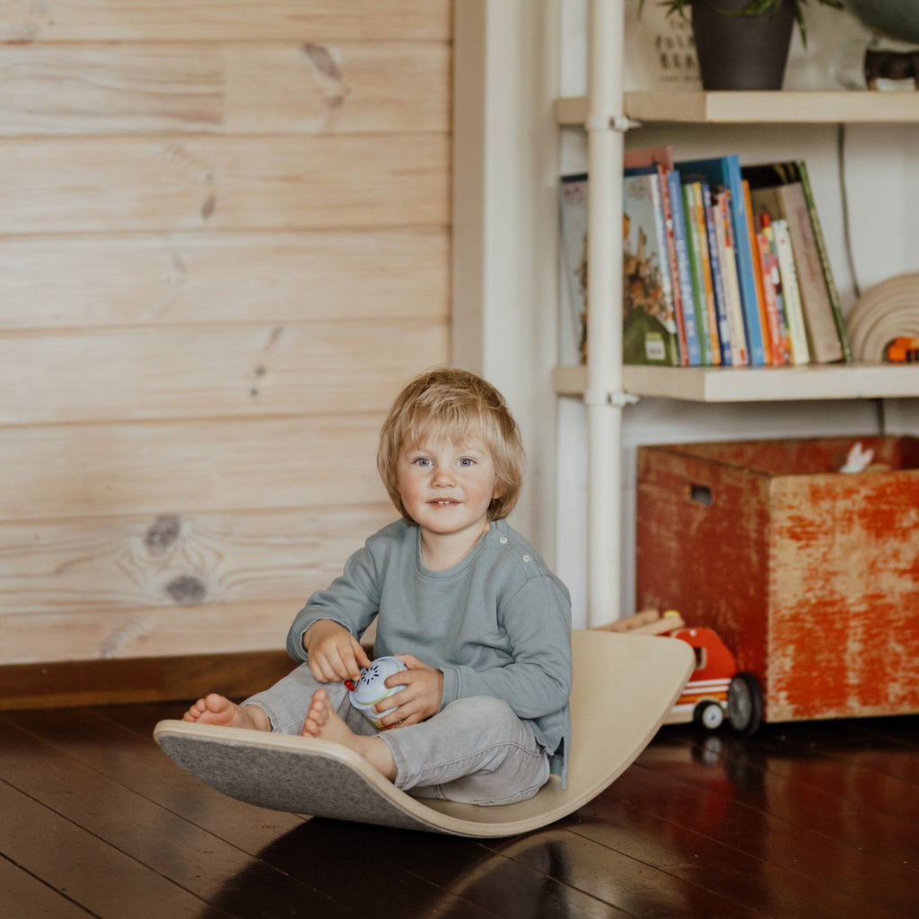 elegant wooden balance board with grey felt, displayed as a minimalist sculpture in a modern living space