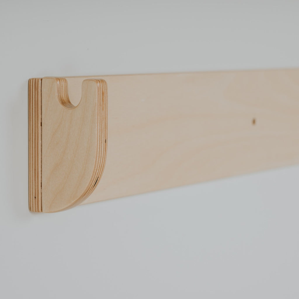 a child's hand testing the grip on the birch plywood climbing wall