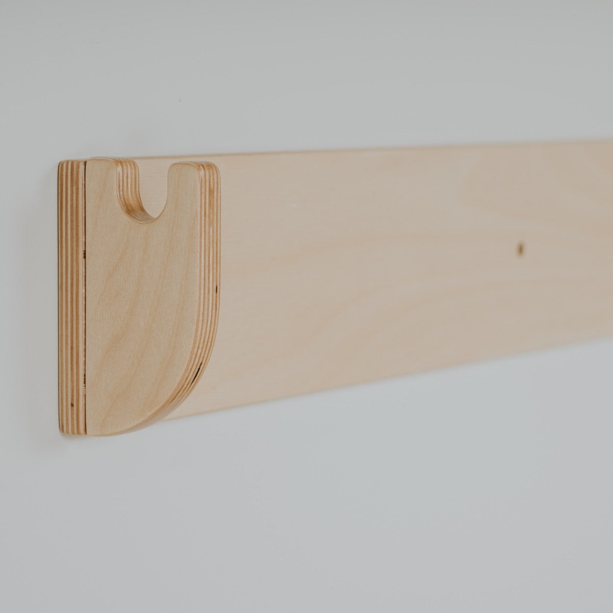 a child's hand testing the grip on the birch plywood climbing wall