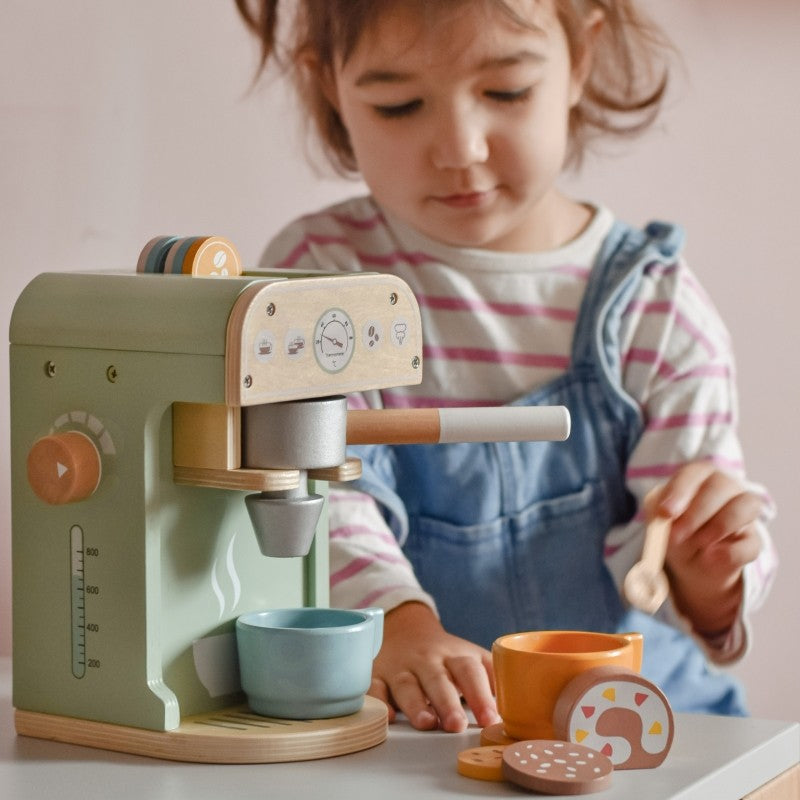 soft morning light on a child's hands serving pretend coffee from a green wooden playset