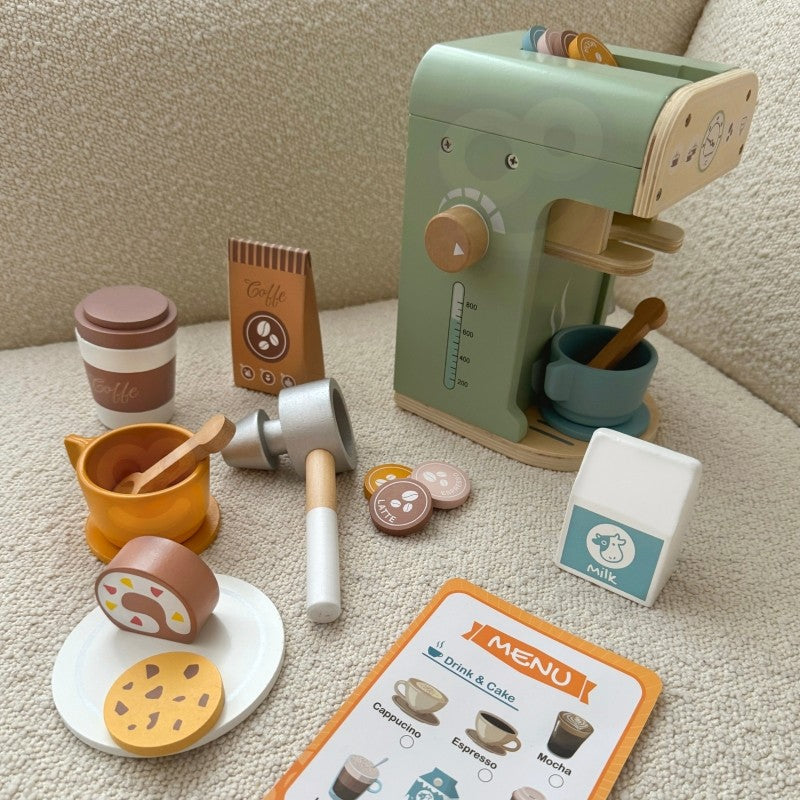 child's hands arranging wooden coffee maker set with green machine and pastries on a sunlit table