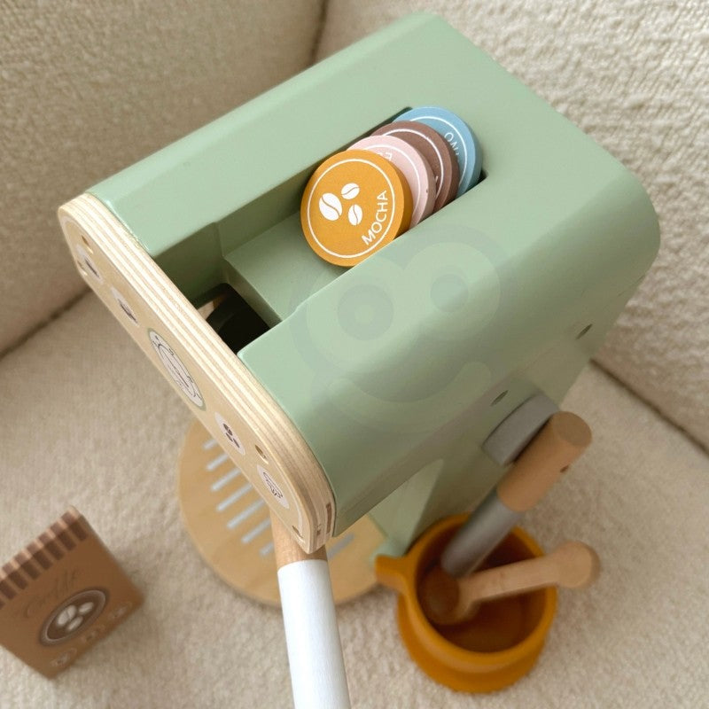 child's hands arranging the woopie green wooden coffee maker playset on a sunlit table