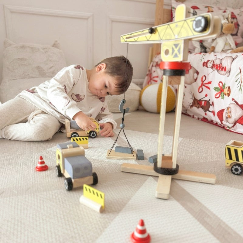 a child's hands carefully placing a wooden block onto the sustainable woopie green construction crane