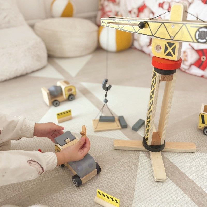 a child's hands carefully placing a wooden block onto the towering 42 cm crane