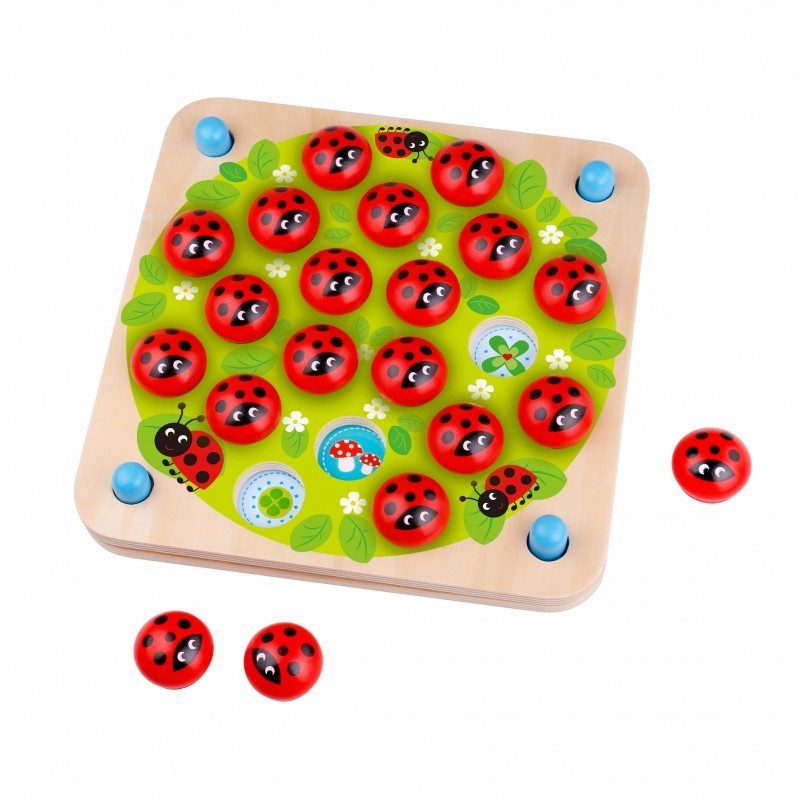close-up of a child's hands playing with a ladybug memory puzzle on a sunlit wooden table