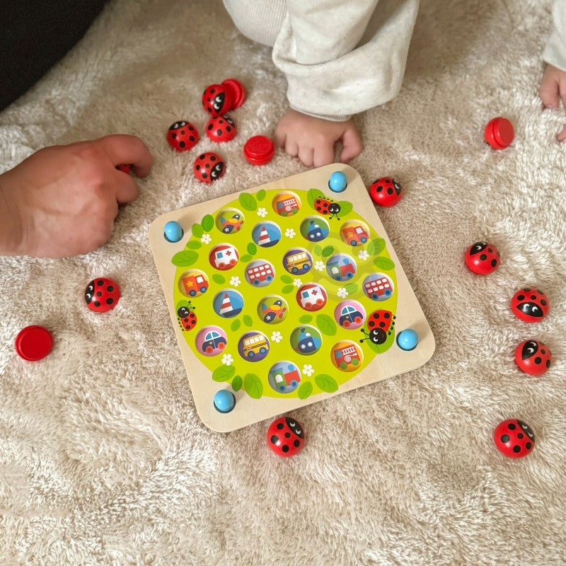 close-up of a child's hands playing with the ladybug memory puzzle on a sunlit wooden table