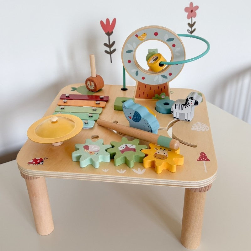 a toddler's hands playing with the colorful gear spinner on the woopie green wooden activity table