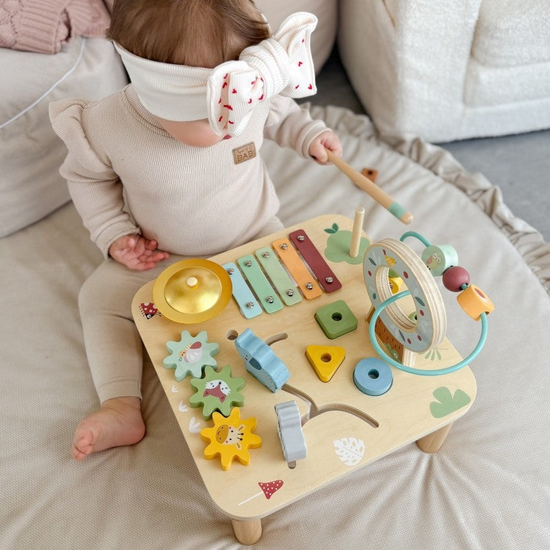 child's hands playing with the colorful gear spinner on a sustainable wooden activity table