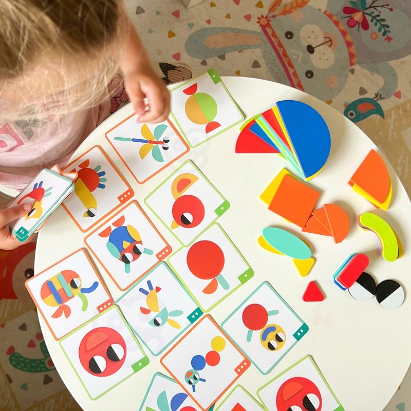 close-up of a child's hands arranging colorful wooden butterfly puzzle pieces on a sunlit table