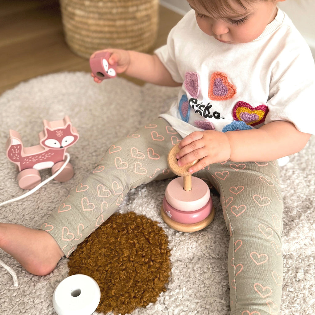 elegant pastel wooden fox pull toy and stacking pyramid on a neutral-toned shelf, showcasing refined toddler play